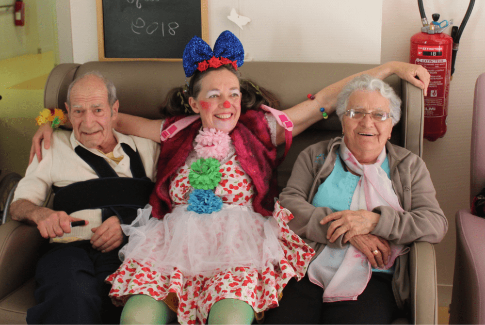 Clown posant, assis avec deux résidents d'Ehpad